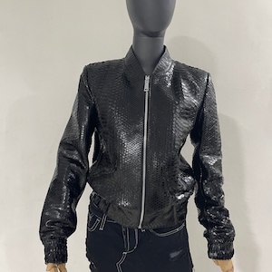 May include: A black leather bomber jacket with a snakeskin pattern. The jacket has a zipper closure and a ribbed collar, cuffs, and hem.