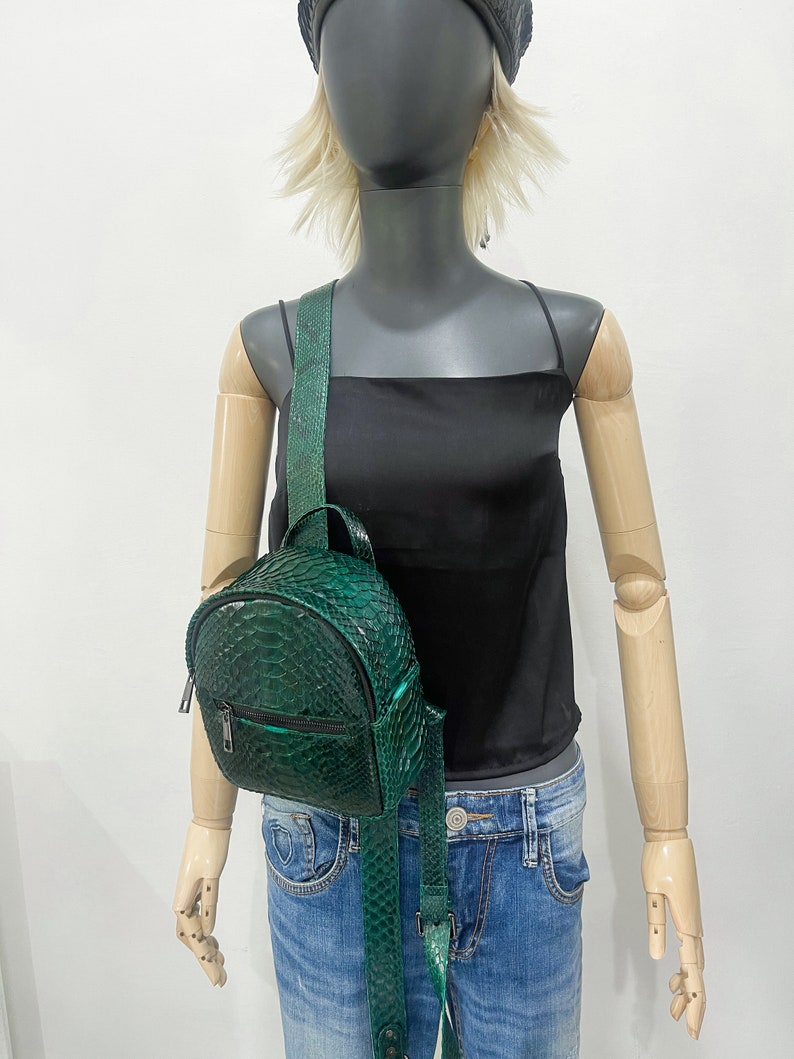 Peut inclure: Un petit sac &agrave; dos en cuir de serpent vert avec une poche zipp&eacute;e et des bretelles r&eacute;glables.