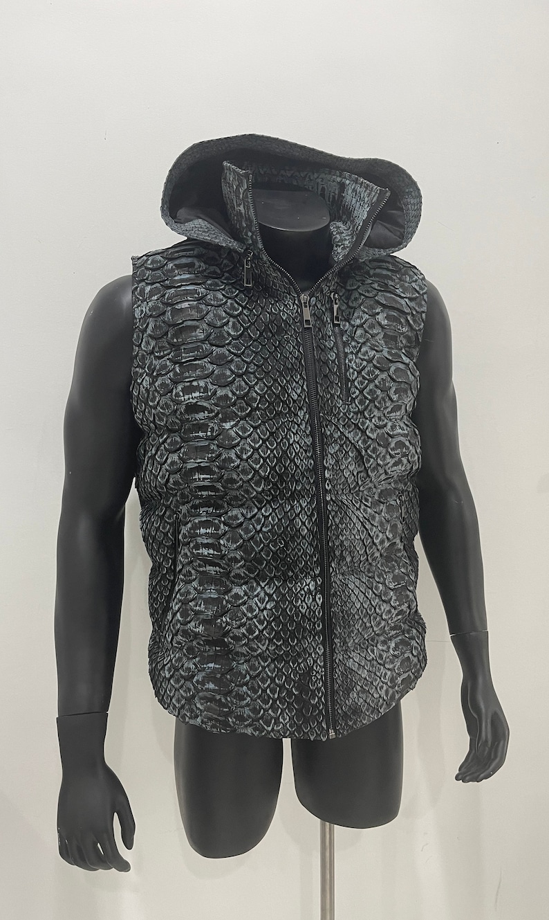May include: A sleeveless hooded vest with a black and green snake skin pattern. The vest has a zip closure and a stand-up collar.
