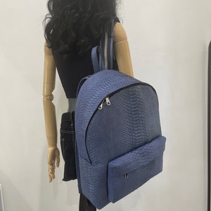 K&ouml;nnte beinhalten: Ein blauer Rucksack aus Schlangenleder mit einer Fronttasche und silbernen Beschl&auml;gen.