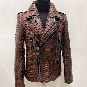 以下が含まれることがあります： 蛇柄のブラウンレザーのジャケットで、複数のジッパーが付いています