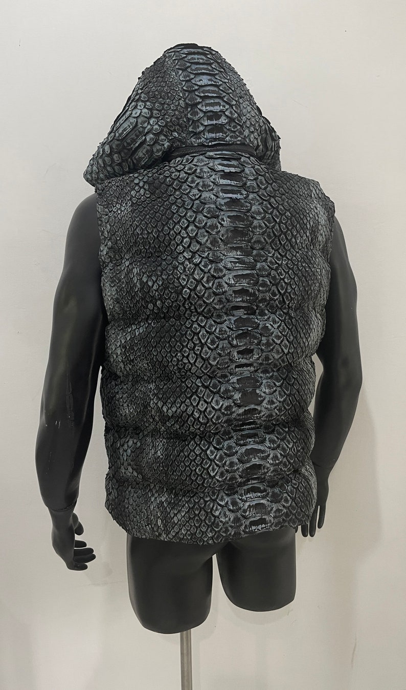May include: A black sleeveless puffer vest with a snakeskin pattern. The vest has a hood and a zip closure.