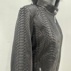 May include: A black leather jacket with a snakeskin pattern. The jacket features a zip fastening and a stand-up collar.