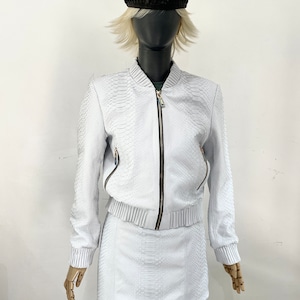 May include: A white snakeskin bomber jacket and matching mini skirt. The jacket features a zip fastening and a ribbed waistband. The skirt has a simple design.