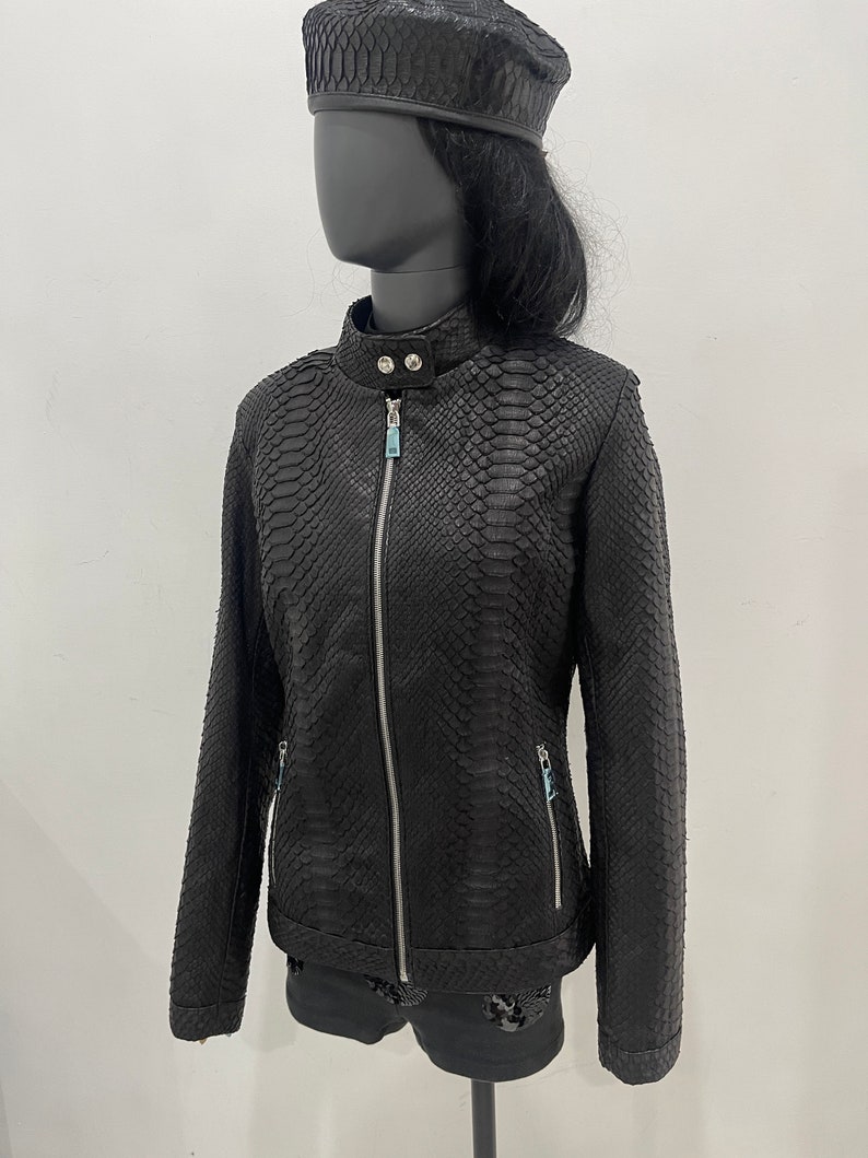 May include: Black leather jacket with a snakeskin pattern and a zip closure. The jacket has a stand-up collar and long sleeves.