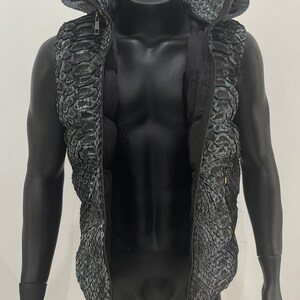 May include: A black sleeveless vest with a zip fastening and a hood. The vest has a snakeskin pattern.