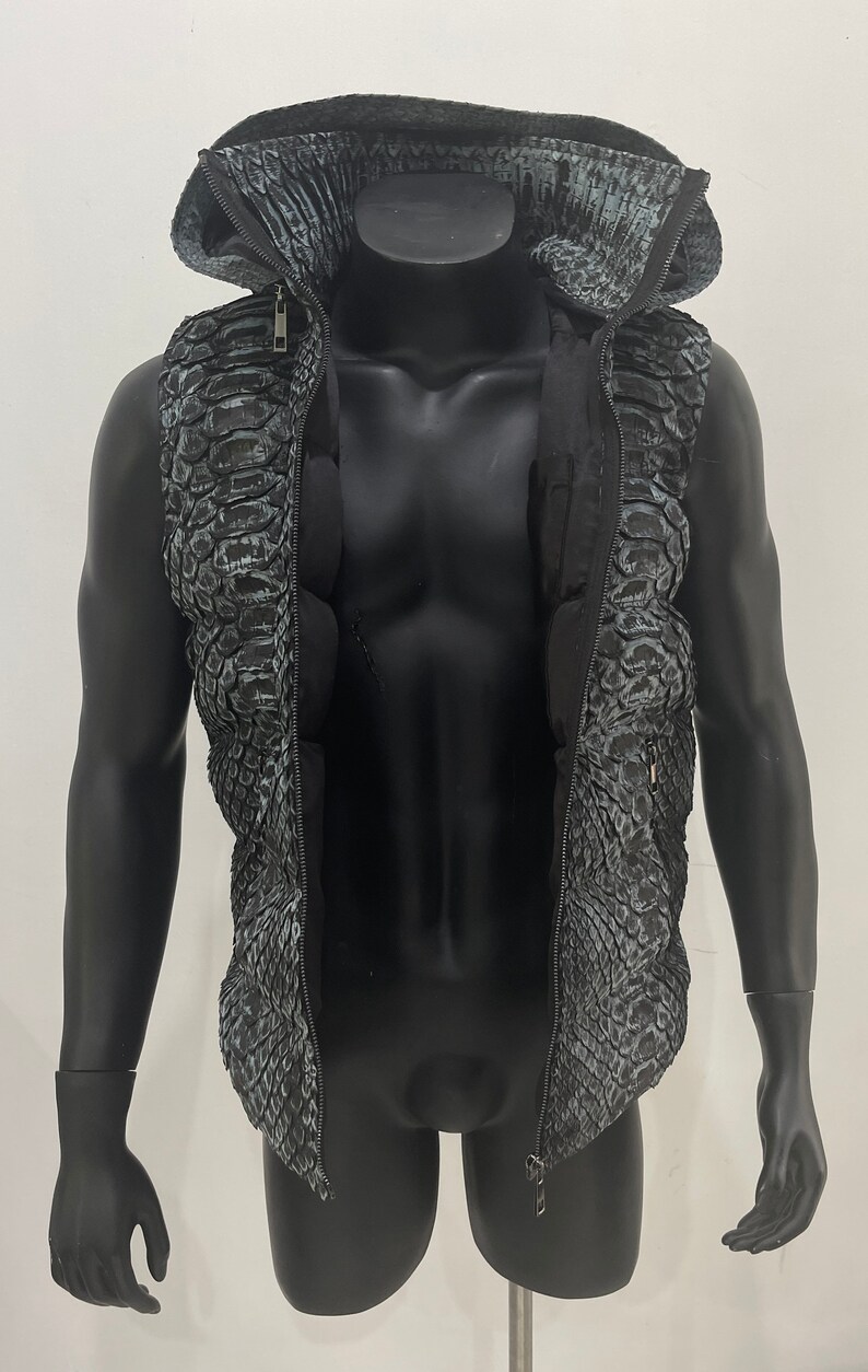 May include: A black sleeveless vest with a zip fastening and a hood. The vest has a snakeskin pattern.