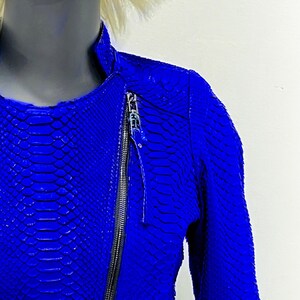 K&ouml;nnte beinhalten: Eine blaue Lederjacke mit Schlangenhautmuster und Rei&szlig;verschluss.