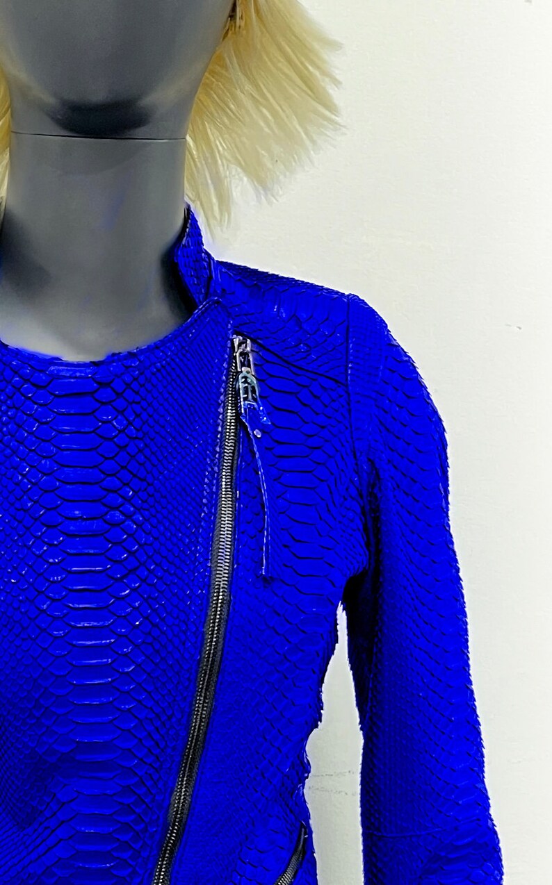 K&ouml;nnte beinhalten: Eine blaue Lederjacke mit Schlangenhautmuster und Rei&szlig;verschluss.