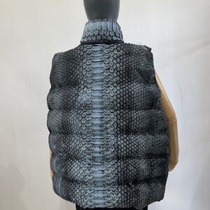 May include: A black puffer vest with a snakeskin pattern. The vest has a high collar and a quilted design.