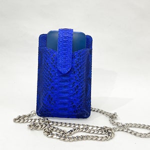 May include: A blue snakeskin phone case with a silver chain strap.
