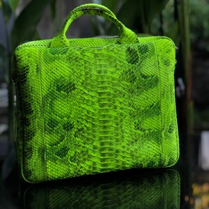 May include: A bright green snakeskin leather briefcase with a top handle and a zip closure.