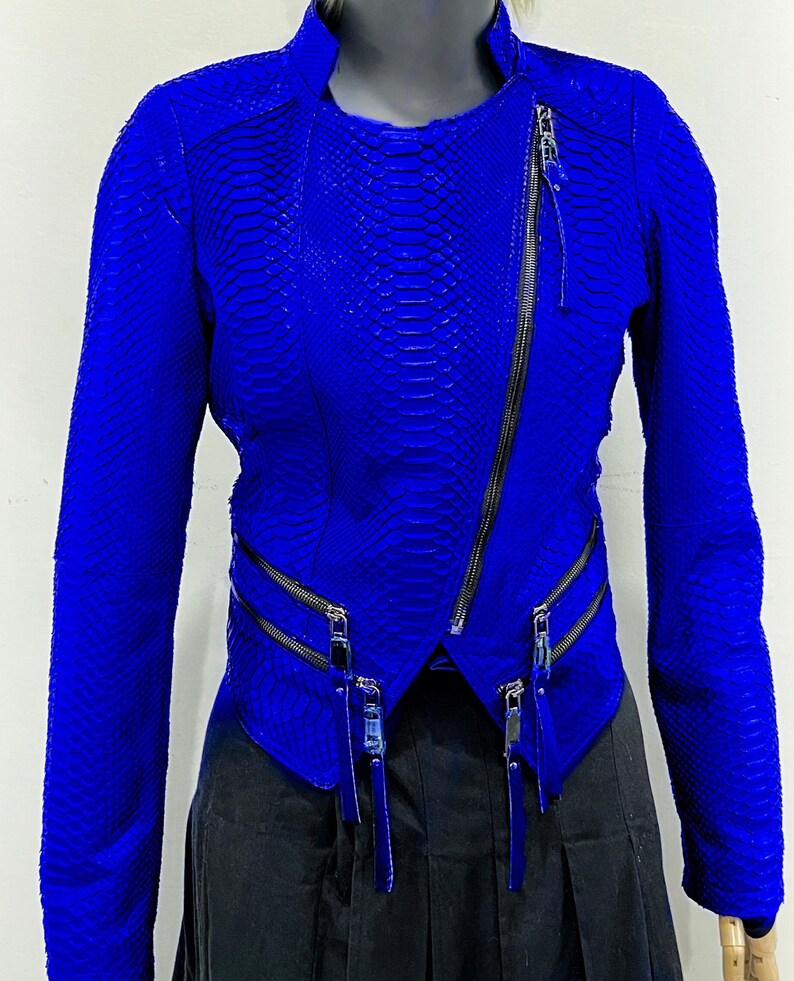 K&ouml;nnte beinhalten: Eine leuchtend blaue Lederjacke mit Schlangenhautmuster und mehreren Rei&szlig;verschl&uuml;ssen.