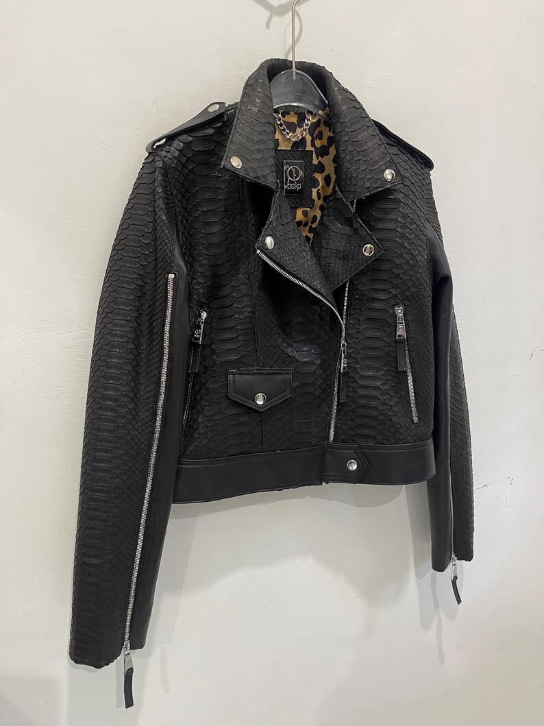 Może przedstawiać: Czarna sk&oacute;rzana kurtka ze wzorem sk&oacute;ry węża i podszewką w panterkę. Kurtka ma zamek błyskawiczny i dwie kieszenie.