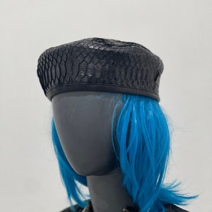 May include: A black leather beret with a snakeskin pattern.