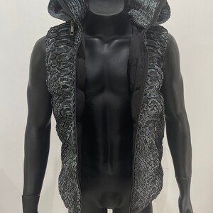 May include: A black sleeveless jacket with a zip fastening and a hood. The jacket has a snakeskin pattern.