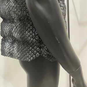 May include: A black snakeskin vest with a quilted design. The vest is on a mannequin.
