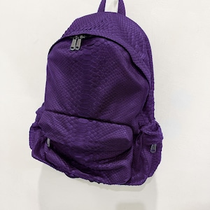 May include: A purple snakeskin backpack with a zip closure and a small pocket on the front.