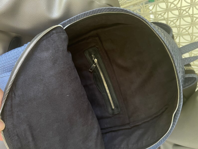 K&ouml;nnte beinhalten: Ein blauer Rucksack mit einer Rei&szlig;verschlusstasche im Inneren. Der Rucksack ist aus einem strukturierten Material gefertigt.