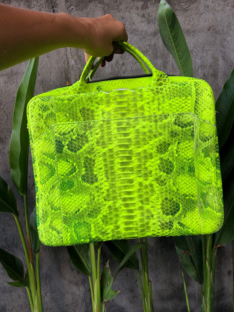 May include: A bright green snakeskin laptop bag with a top handle.