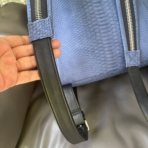 K&ouml;nnte beinhalten: Ein blauer Schlangenleder-Rucksack mit schwarzen verstellbaren Tr&auml;gern und silbernen Rei&szlig;verschl&uuml;ssen.