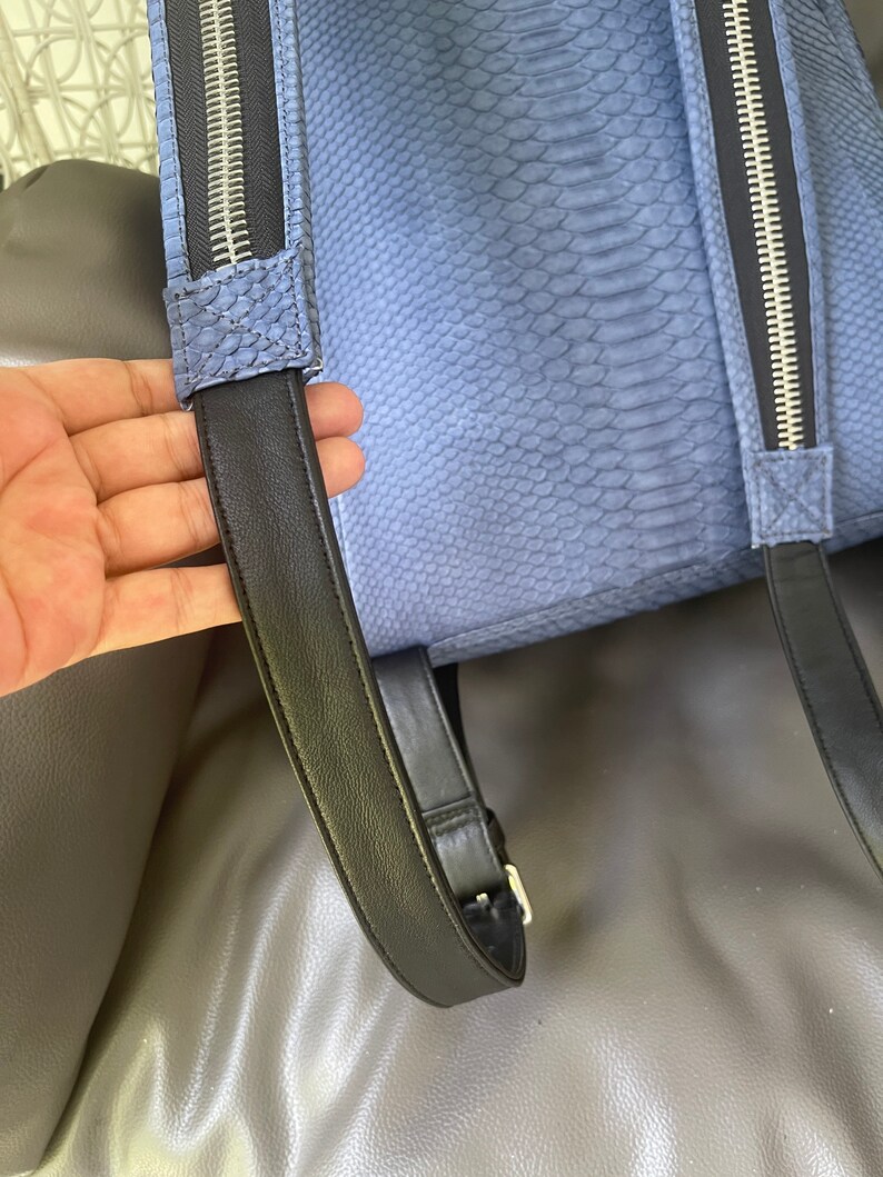 K&ouml;nnte beinhalten: Ein blauer Schlangenleder-Rucksack mit schwarzen verstellbaren Tr&auml;gern und silbernen Rei&szlig;verschl&uuml;ssen.