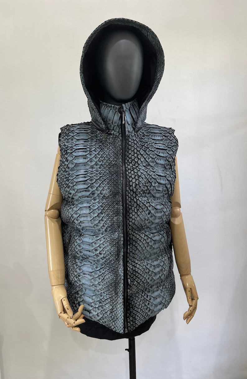 May include: A sleeveless hooded vest made of blue and black snakeskin. The vest has a zip fastening and a stand-up collar.