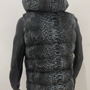 May include: A black puffer vest with a snakeskin pattern. The vest has a hood and is sleeveless.