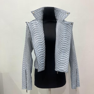 May include: A light blue snakeskin leather jacket with a zipper closure. The jacket has a stand-up collar and long sleeves.