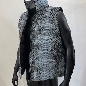May include: A sleeveless puffer vest made of blue snakeskin with a zipper closure. The vest has a stand-up collar and two pockets.