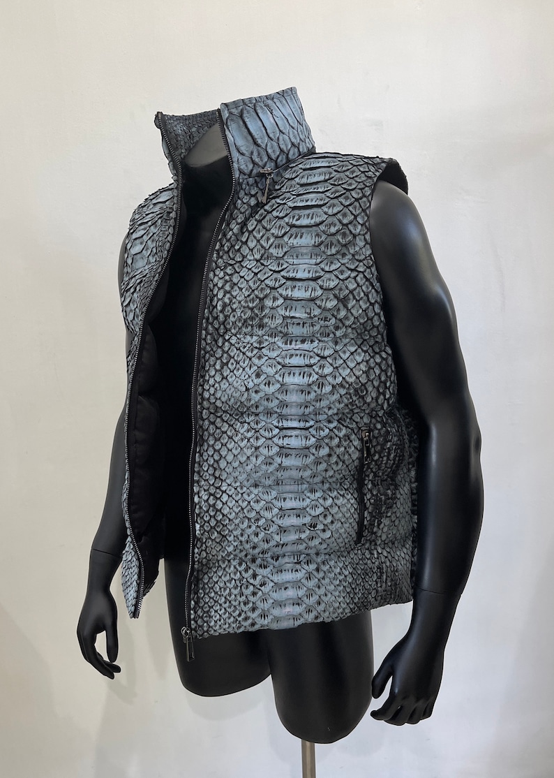 May include: A sleeveless puffer vest made of blue snakeskin with a zipper closure. The vest has a stand-up collar and two pockets.