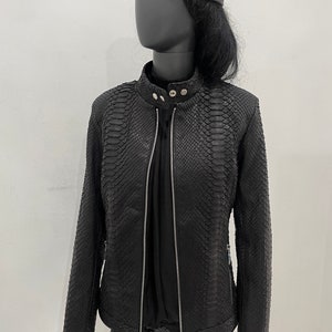 May include: Black leather jacket with a snakeskin pattern. The jacket has a zip fastening and a stand-up collar.