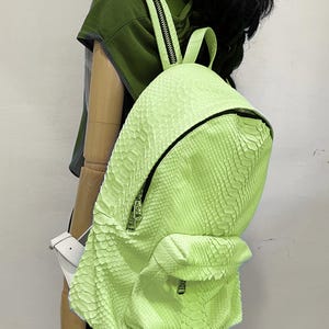 May include: A bright green snakeskin backpack with a zipper closure and a smaller pocket on the front.