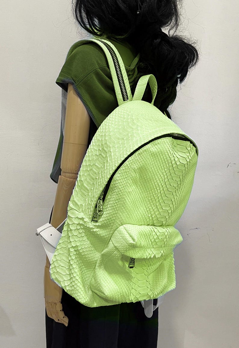 May include: A bright green snakeskin backpack with a zipper closure and a smaller pocket on the front.