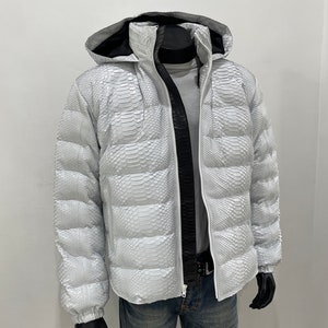 May include: A white puffer jacket with a snakeskin pattern. The jacket has a hood and a zip closure.