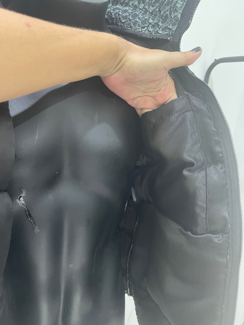 May include: Black puffer jacket with a zip fastening and a black quilted lining. The jacket has a hood with a faux fur trim.