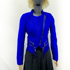 K&ouml;nnte beinhalten: Eine blaue Lederjacke mit Schlangenhautmuster und Rei&szlig;verschlussdetails. Die Jacke hat eine verk&uuml;rzte L&auml;nge und einen Stehkragen.