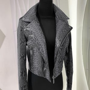 May include: A grey snakeskin leather jacket with a zip fastening and a stand-up collar.