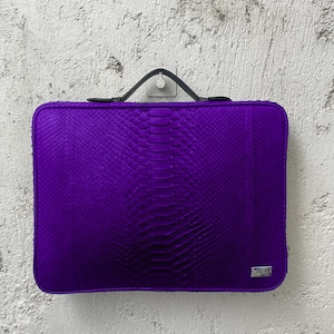 May include: A purple snakeskin laptop sleeve with a black handle and a small silver logo that says "DRAGON".