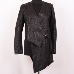 May include: A black leather jacket with a snakeskin pattern and a long, asymmetrical hemline. The jacket has a belt with a buckle at the waist.
