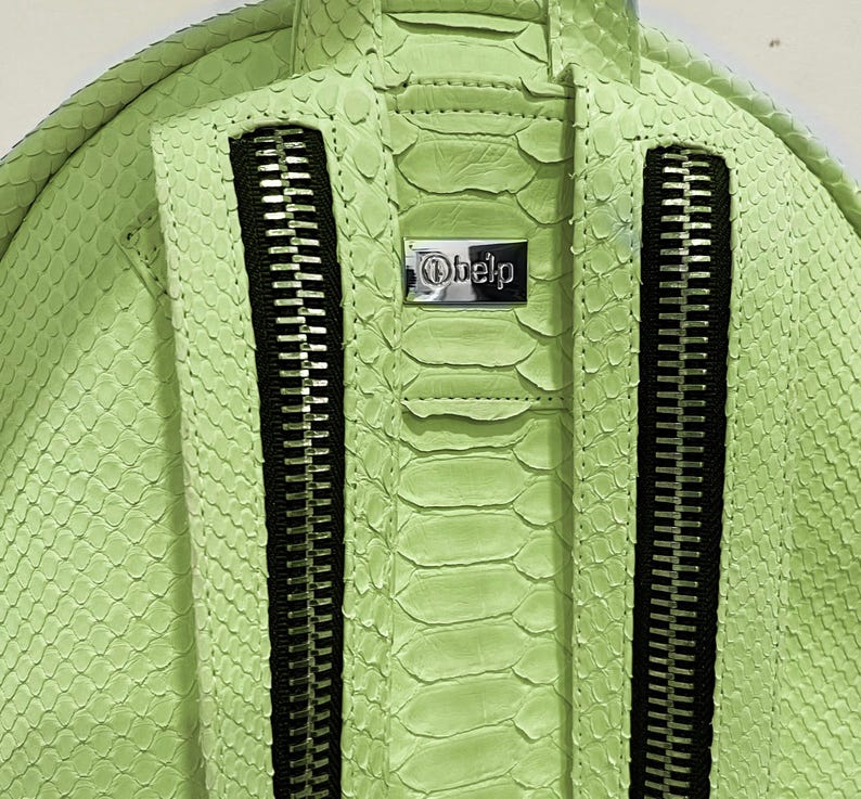 May include: A lime green snakeskin backpack with black zippers and a silver metal tag that says "Obelp".