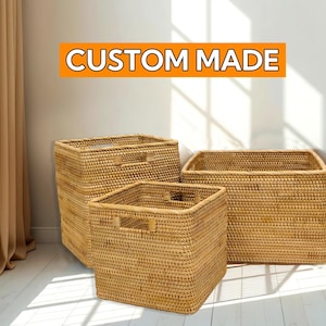 Könnte beinhalten: Drei gewebte rechteckige Aufbewahrungskörbe in verschiedenen Größen. Die Körbe bestehen aus einem hellbraunen Material und haben eingebaute Griffe. Der Text "CUSTOM MADE" wird in einem orangefarbenen Rechteck über den Körben angezeigt.