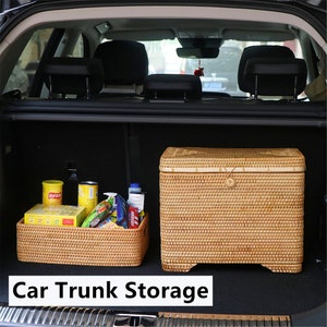 May include: Two woven wicker storage baskets in a car trunk. The larger basket has a lid and is filled with various items, including canned goods and snacks. The smaller basket is empty and is in the foreground. The text "Car Trunk Storage" is printed below the baskets.