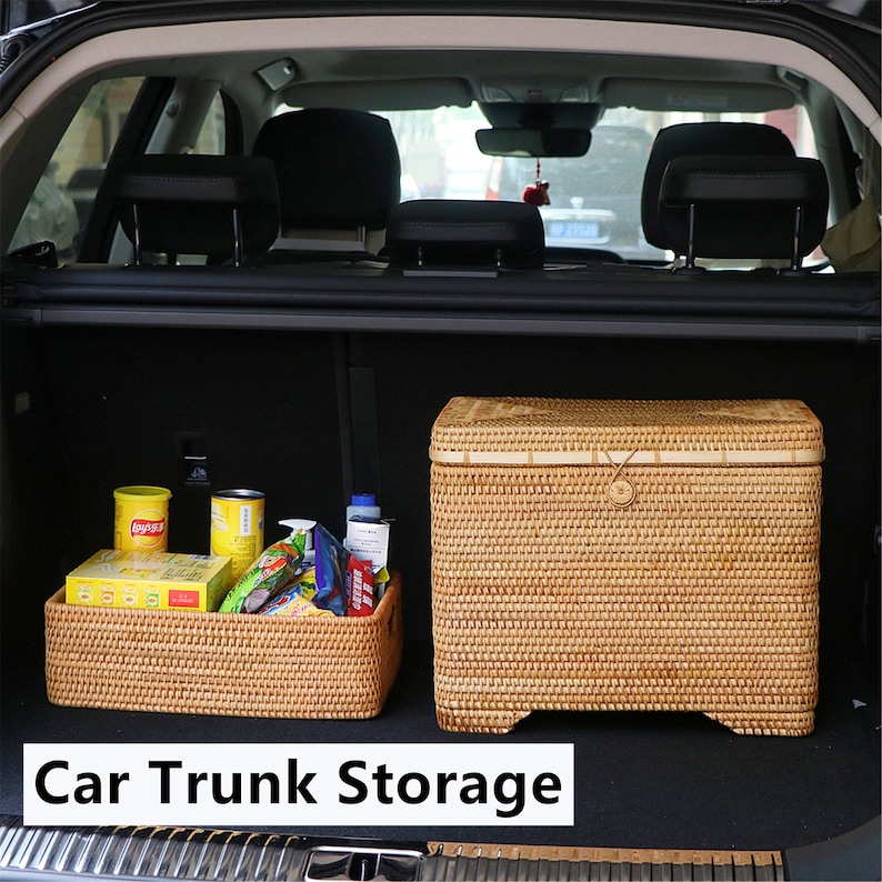 May include: Two woven wicker storage baskets in a car trunk. The larger basket has a lid and is filled with various items, including canned goods and snacks. The smaller basket is empty and is in the foreground. The text "Car Trunk Storage" is printed below the baskets.