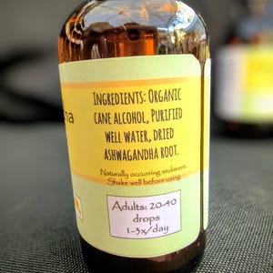 Puede incluir: Una peque&ntilde;a botella de vidrio marr&oacute;n con una etiqueta amarilla. La etiqueta enumera los ingredientes: Alcohol de ca&ntilde;a org&aacute;nico, agua purificada, ra&iacute;z de Ashwagandha seca. Instrucciones de dosificaci&oacute;n: 20-40 gotas, 1-3 veces/d&iacute;a.