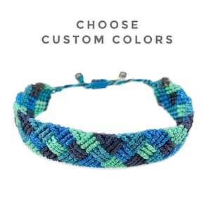 May include: A blue, green, and navy macrame bracelet with adjustable sliding knots. The bracelet features a woven pattern and the text "CHOOSE CUSTOM COLORS" in gray.