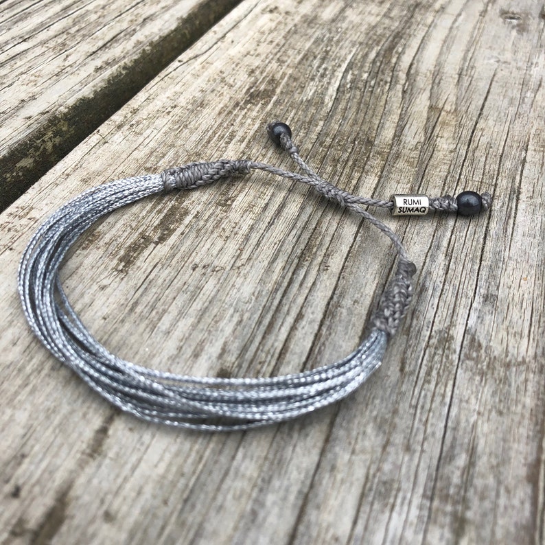 Minimalist silver string bracelet, handcrafted for Parkinson’s, dyslexia, and schizophrenia awareness. This silver awareness ribbon bracelet is lightweight, stylish, and size-adjustable for men, women and kids. A meaningful awareness jewelry piece to support various causes including sciatic pain, Parkinsons Disease and neurological disorders. A thoughtful gift for those affected by these conditions. Handmade by Rumi Sumaq, silver awareness jewelry, awareness wristband, silver string bracelet.