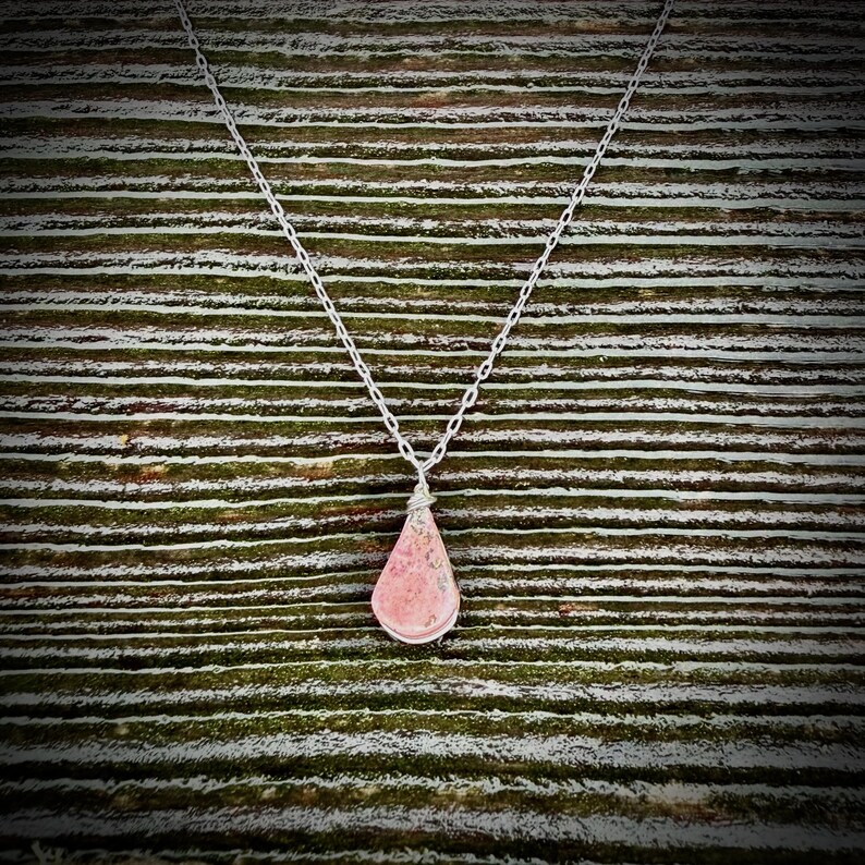 Minimalist teardrop Rhodonite pendant necklace in sterling silver, featuring a soft pink natural stone with subtle black veining. Handcrafted by Quechua jewelry designer Coco Paniora Salinas on Martha’s Vineyard in the RumiSumaq art jewelry studio. Perfect for everyday wear or layering, this versatile, modern necklace offers understated elegance, meaningful artisan-made design, gentle energy, and the signature style of Rumi Sumaq. It makes a beautiful Mother's Day gift or Valentine's Day present