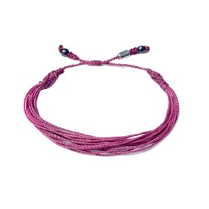 May include: A burgundy braided cord bracelet with black beads and a silver charm that says "The Giving Keys".