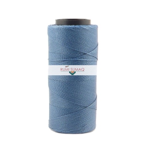 May include: A spool of blue cotton thread with the label "RUMI SUMAQ" on it.